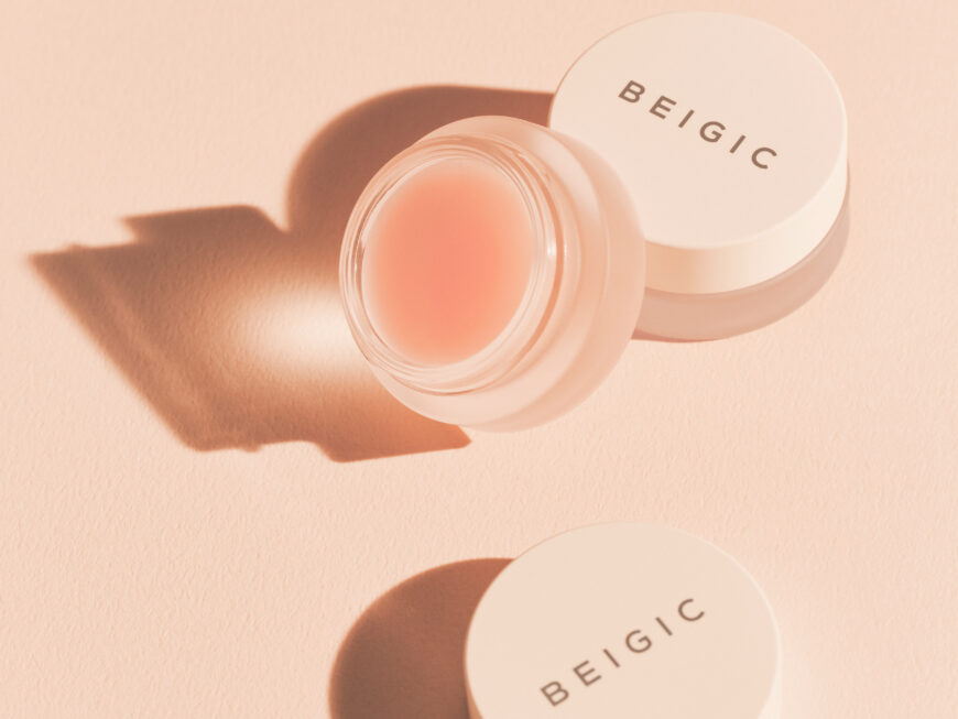 Beigic balzam za usne, prikazan s otvorenim i zatvorenim poklopcem u pastelnim nijansama, povezan s divote cosmetics i korejskom kozmetikom.